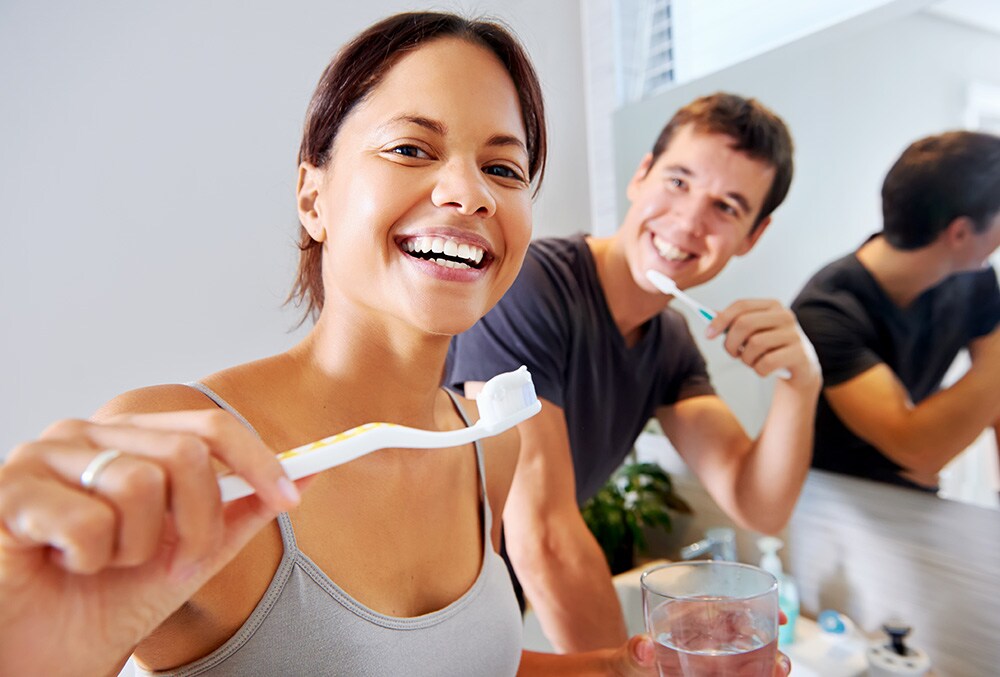 Couple smiling and brushing their teeths