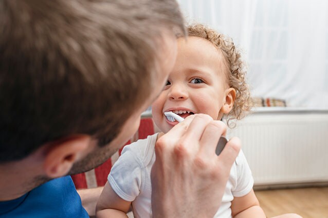 Men brushing his daugther teeth