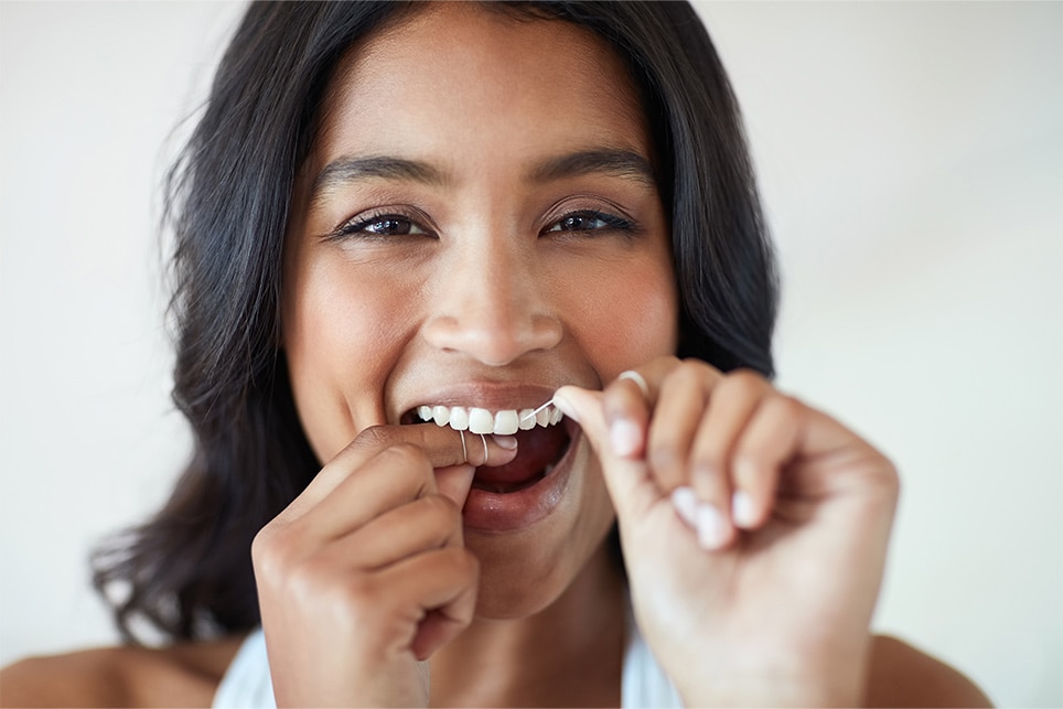 Happy young woman flossing her teeth with colgate