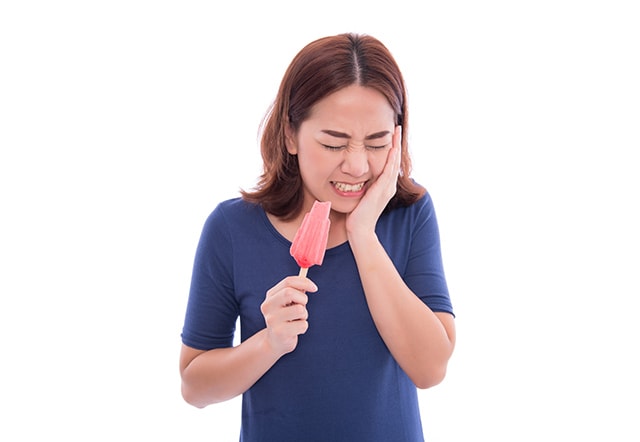 Woman with hipersensitivity eating ice lolly