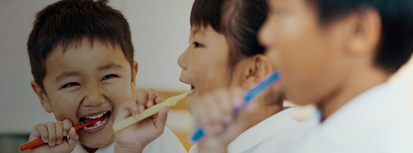 Two children, boy, and girl smiling at each other brushing their teeth Two children, boy, and girl smiling at each other brushing their teeth