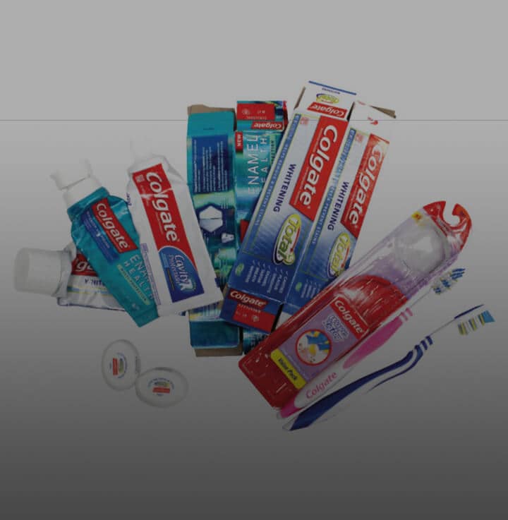 Pile of recyclable Colgate product boxes, toothpaste tubes, and toothbrushes