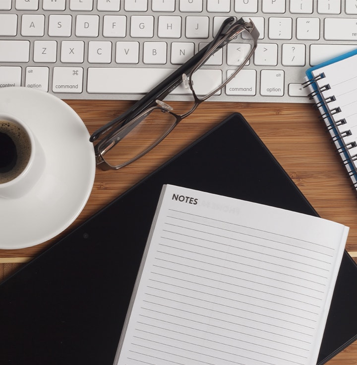 table with keyboard, glasses coffee and notebook